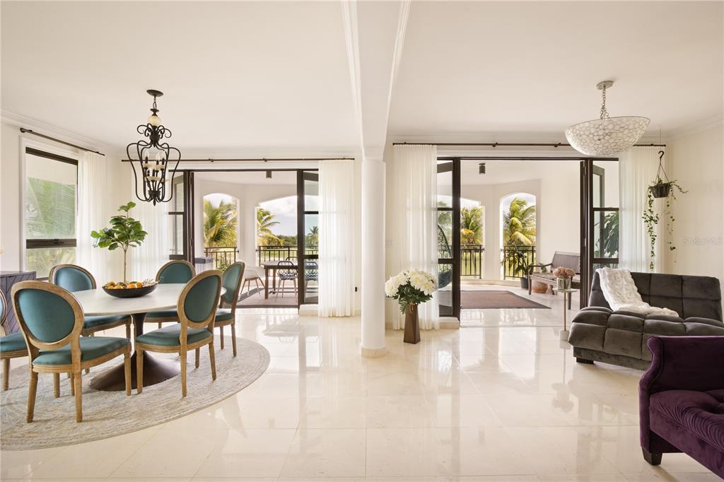 A bright, open-concept dining and living area with tile floors, large glass doors, and balconies — 400 COCO BEACH UNIT 301, RIO GRANDE, PR