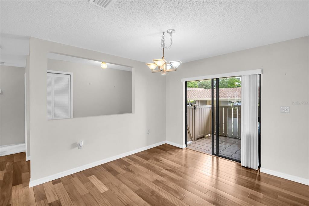 A dining area with wood-look flooring, a chandelier, and a sliding glass door to a patio — 120 EVELYN COURT, OLDSMAR, FL