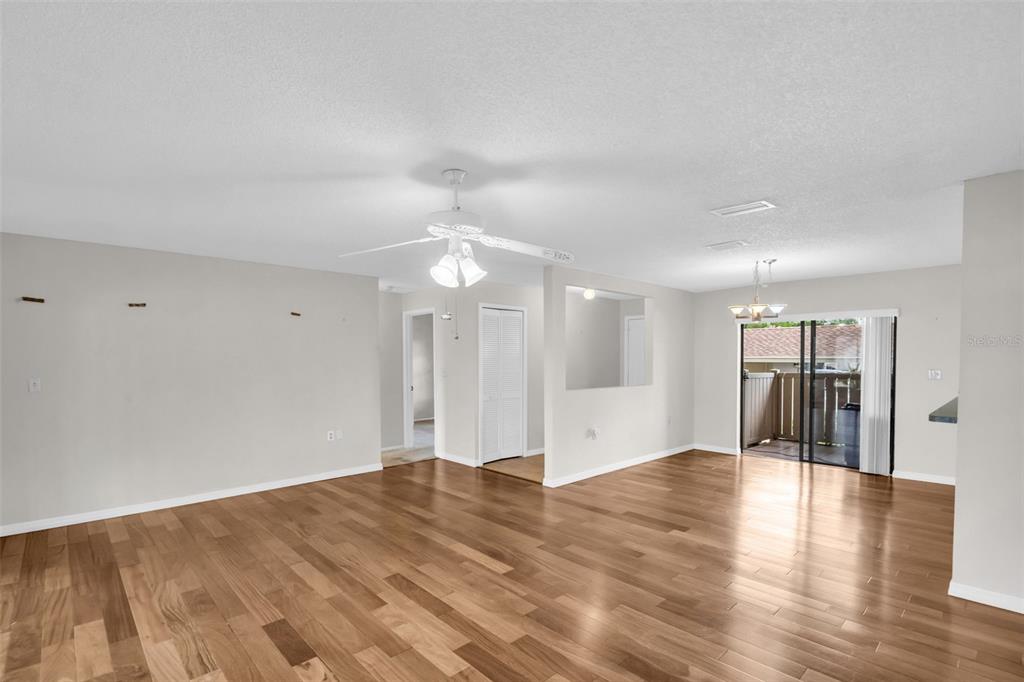 An open-concept living and dining area features wood-look flooring, a ceiling fan, and sliding doors — 120 EVELYN COURT, OLDSMAR, FL