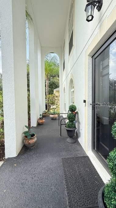 A covered outdoor walkway features white columns, potted plants, and a dark textured floor — 218 TRES REYES LANE, GROVELAND, FL