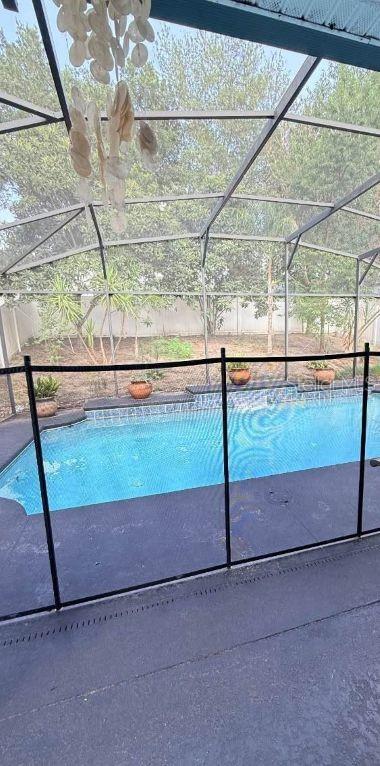 A swimming pool with a safety fence is enclosed by a screened lanai — 218 TRES REYES LANE, GROVELAND, FL