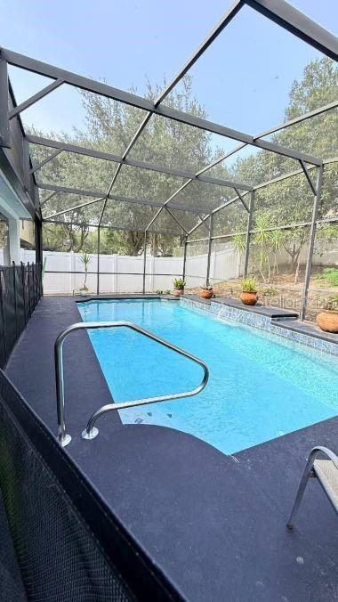 A screened-in swimming pool with a dark deck and a white privacy fence in back — 218 TRES REYES LANE, GROVELAND, FL