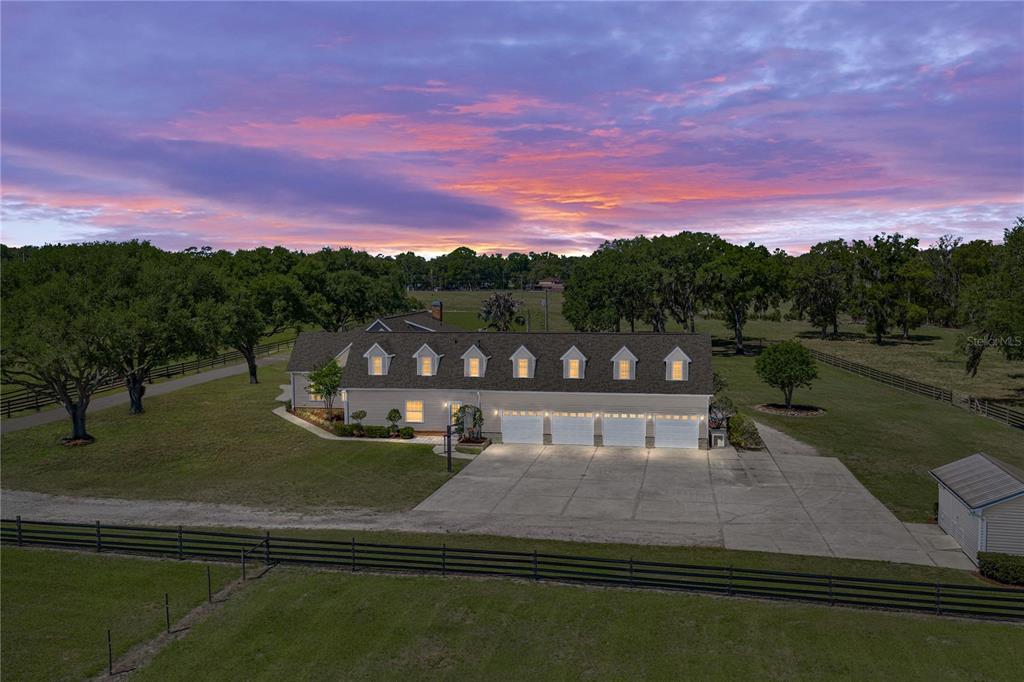 An aerial view of a long, single-story house with a four-car garage at sunset — 29001 BAYHEAD ROAD, DADE CITY, FL