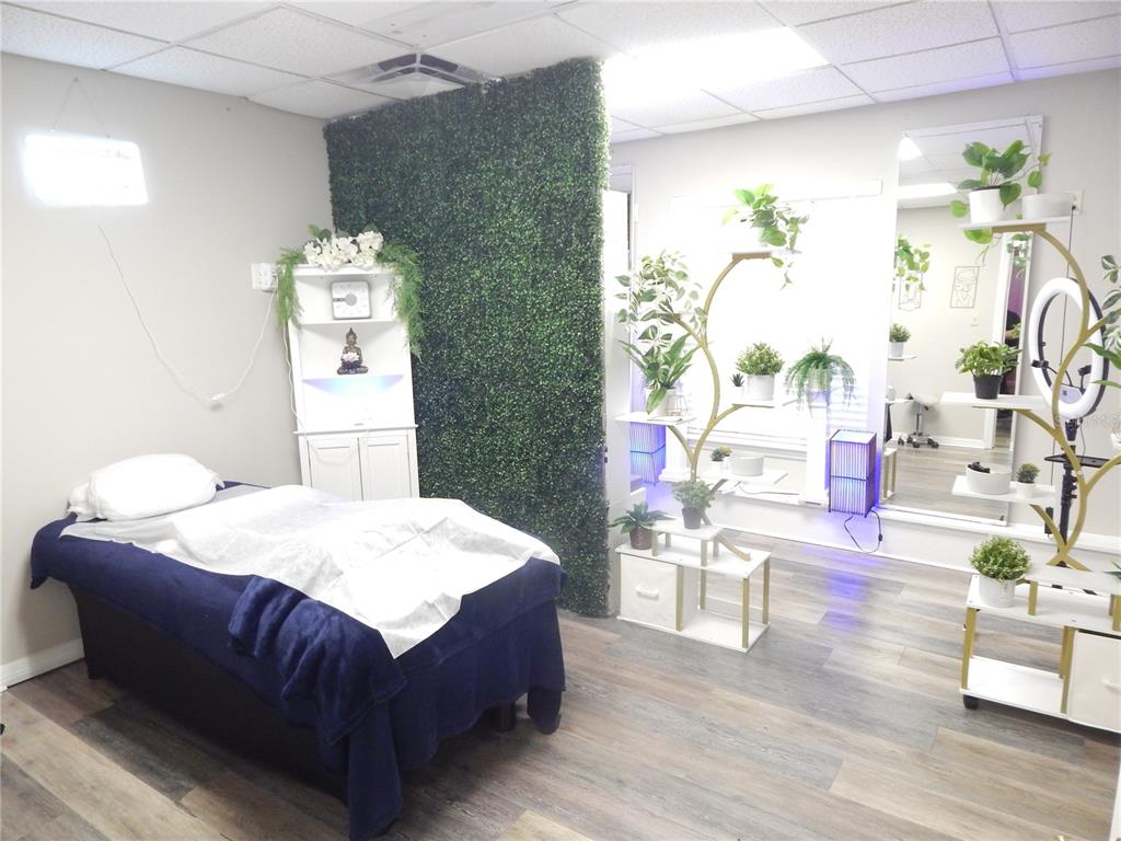 A spa treatment room features a massage table, a green wall divider, and decorative shelving — 705 E OAK STREET UNIT B, KISSIMMEE, FL