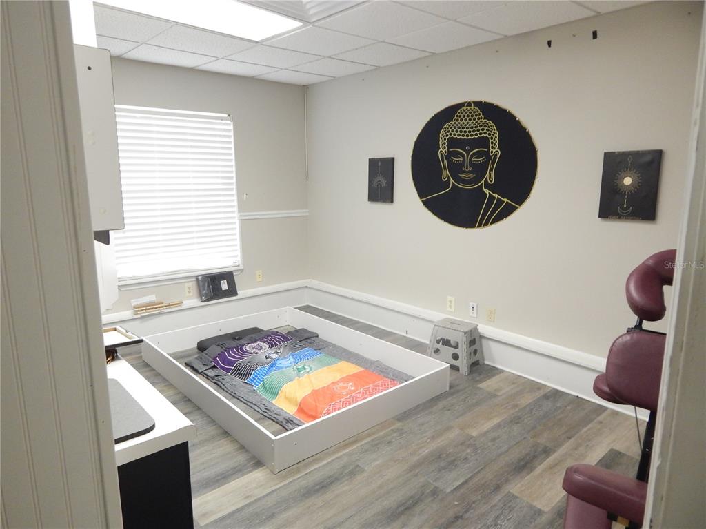 A room features a low white bed frame, a Buddha wall hanging, and wood-look flooring — 705 E OAK STREET UNIT B, KISSIMMEE, FL