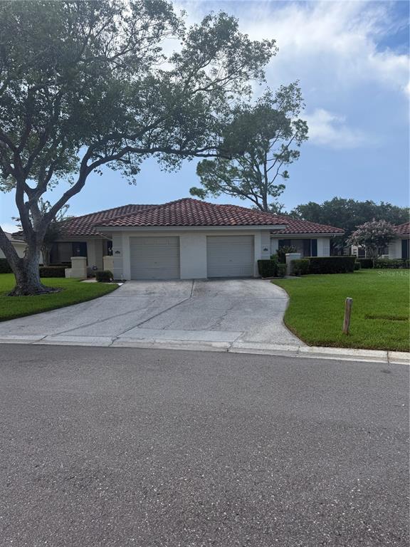 A single-story house with a tiled roof, garage, and manicured hedges in the front yard — 18425 AINTREE COURT, TAMPA, FL