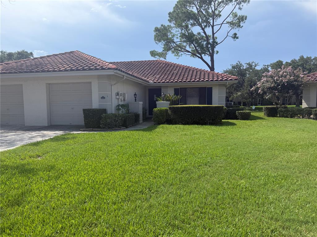 A stucco house exterior features a garage, a walkway leading to a dark green front door — 18425 AINTREE COURT, TAMPA, FL