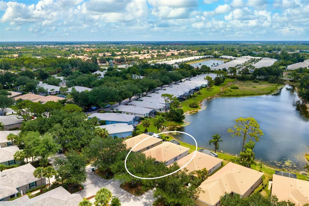 An aerial view shows a residential duplex with a tan tile roof near a lake — 880 CHALMERS DRIVE UNIT 880, VENICE, FL