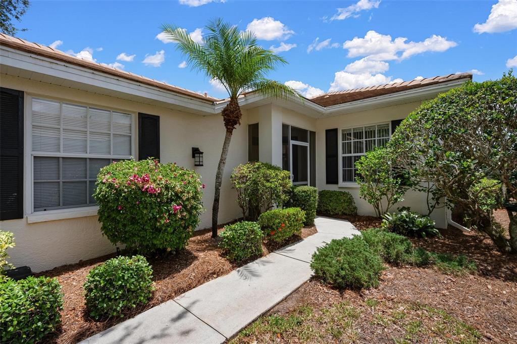 A concrete walkway leads to the front entrance of a house with a palm tree — 880 CHALMERS DRIVE UNIT 880, VENICE, FL