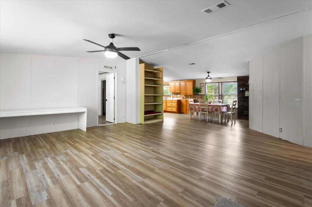 An open-concept living and dining area features light wood-look flooring and a ceiling fan — 173 SW BOUNDARY WAY, FORT WHITE, FL