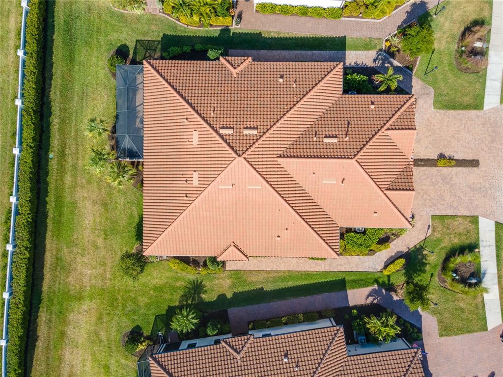 An aerial view shows the tiled roof of a house with a screened-in patio area — 6250 PLATEAU COURT, BRADENTON, FL