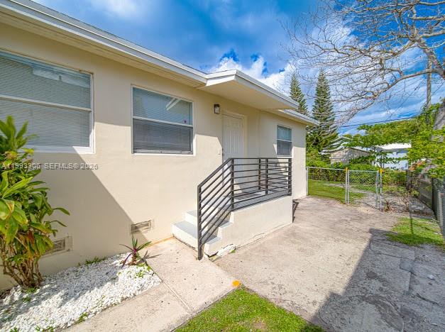A beige exterior wall features a metal staircase leading to a doorway with windows — 1887 NW 48th St # 1887, Miami FL 33142, MIAMI, FL