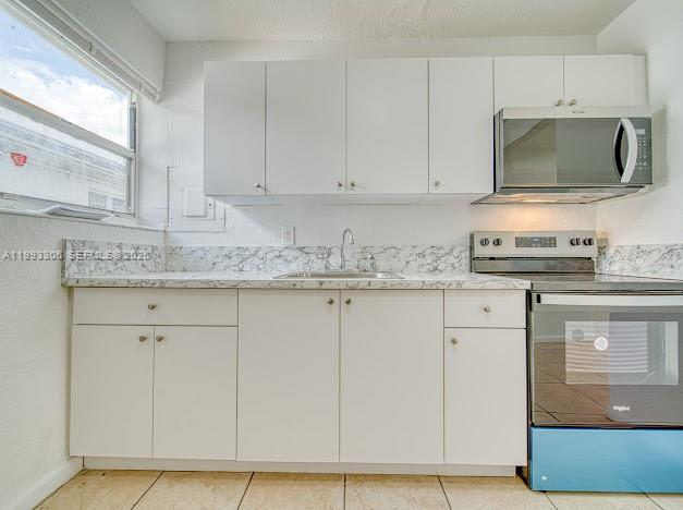 A kitchen features white cabinets, a marble-patterned countertop, and stainless steel appliances — 1887 NW 48th St # 1887, Miami FL 33142, MIAMI, FL