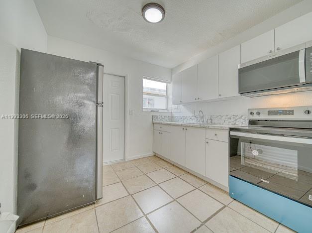 A kitchen features white cabinets, stainless steel appliances, a black refrigerator, and tiled flooring — 1887 NW 48th St # 1887, Miami FL 33142, MIAMI, FL