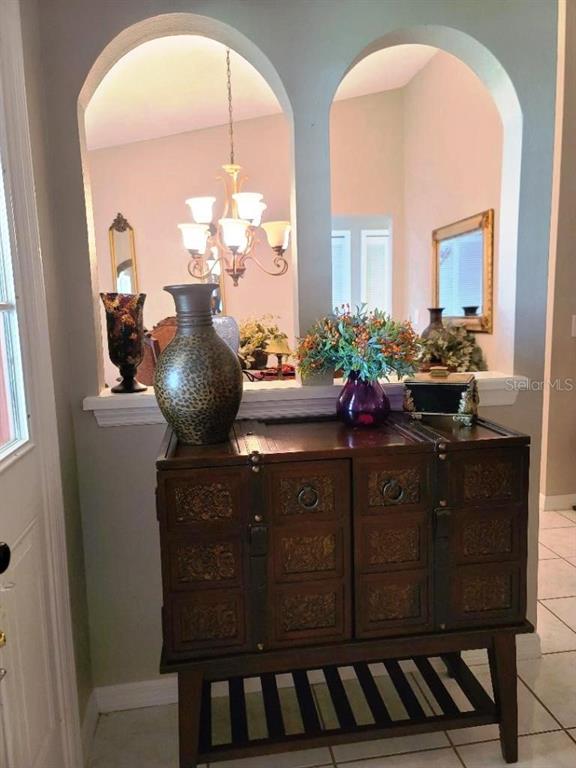 A wooden cabinet with a vase and floral arrangement sits before two arched wall cutouts — 9736 CYPRESS SHADOW AVENUE, TAMPA, FL