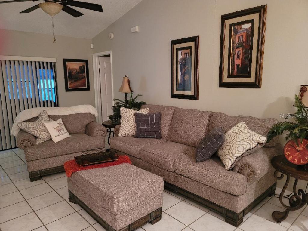 A living room features a sofa, loveseat, and ottoman on a tiled floor — 9736 CYPRESS SHADOW AVENUE, TAMPA, FL