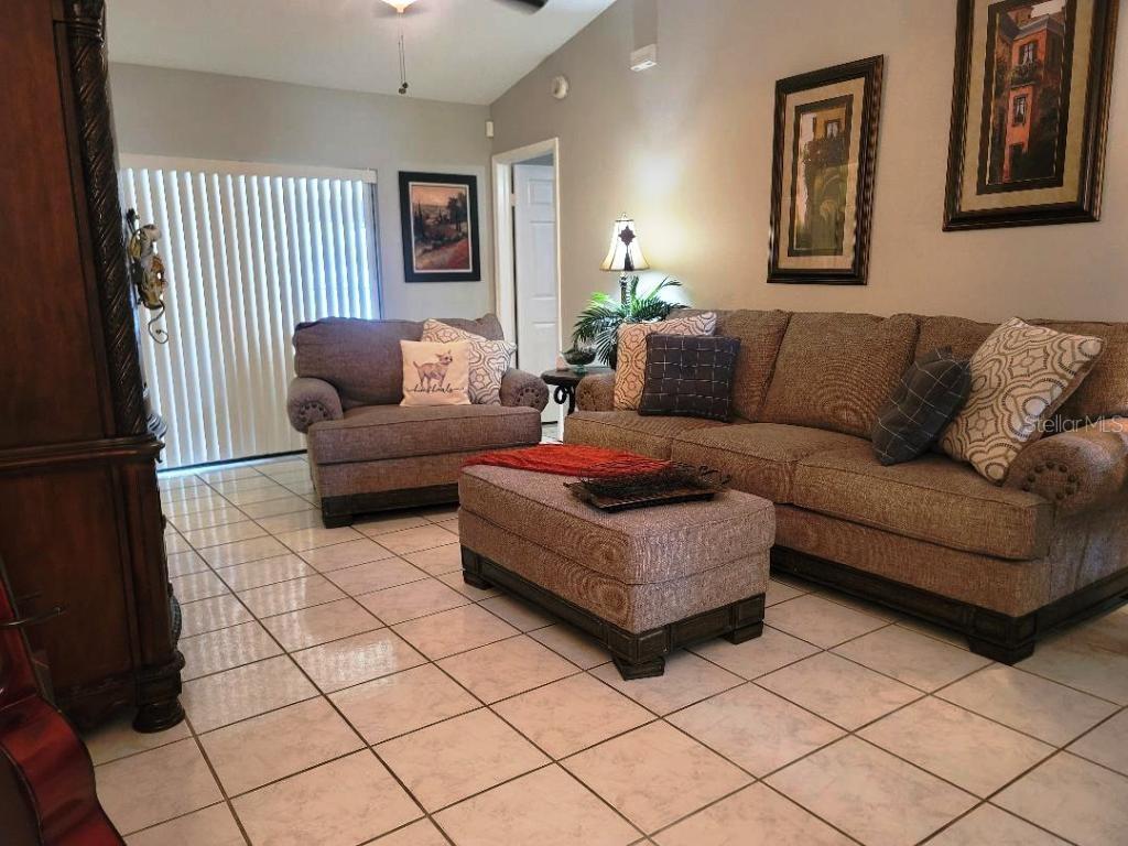A living room with tile floors, a sofa, an armchair, and an ottoman — 9736 CYPRESS SHADOW AVENUE, TAMPA, FL