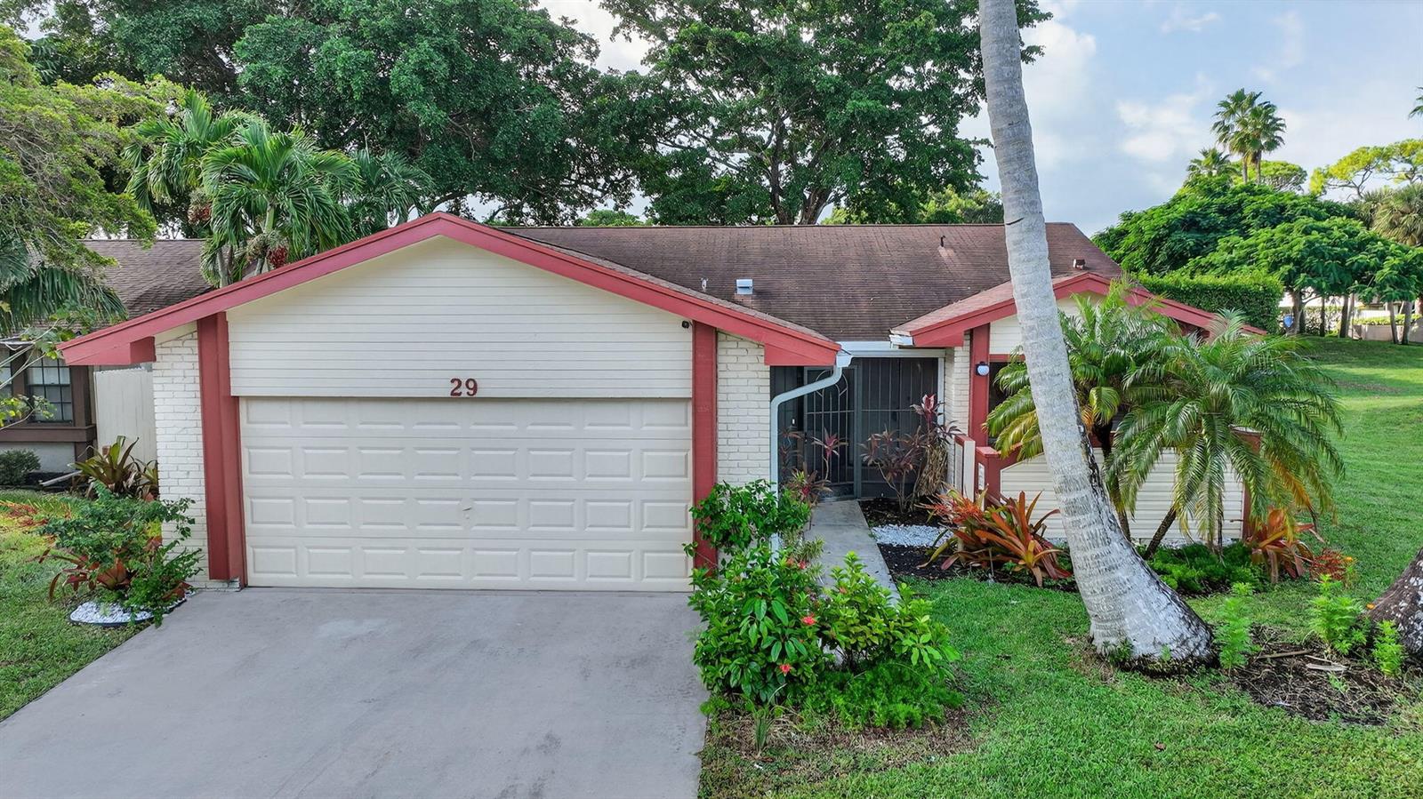 A single-story house with a beige garage, red trim, and a palm tree in front — 29 Fawlkland Circle, Boynton Beach FL 33426, BOYNTON BEACH, FL