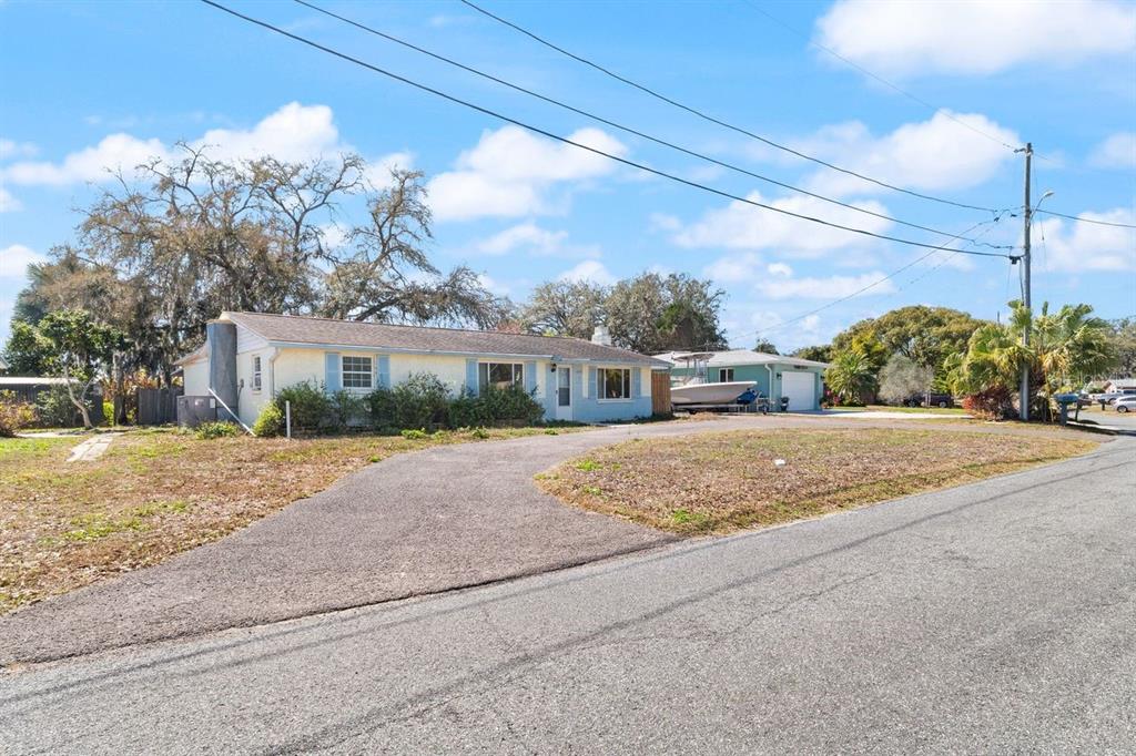 A single-story house with a light blue exterior and a paved driveway sits on a lot — 6870 PARKSIDE DRIVE, NEW PORT RICHEY, FL