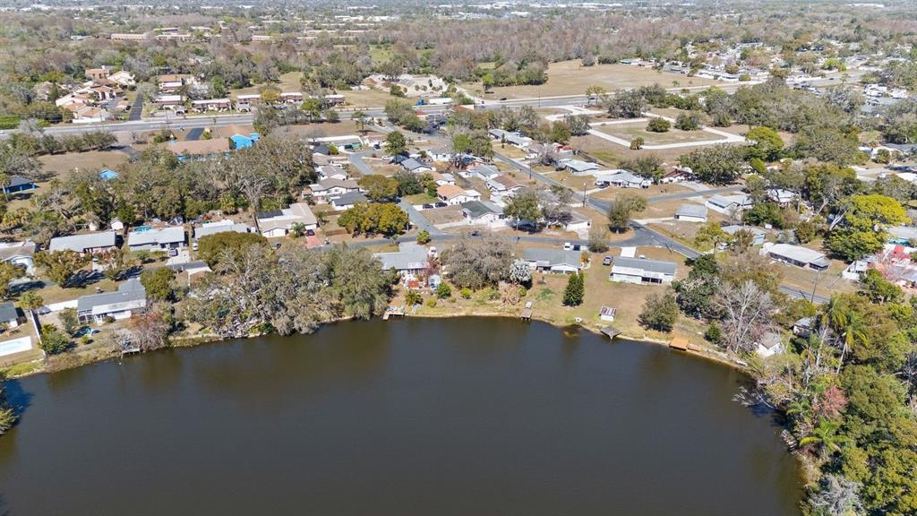 An aerial view shows a residential neighborhood situated along the edge of a lake — 6870 PARKSIDE DRIVE, NEW PORT RICHEY, FL