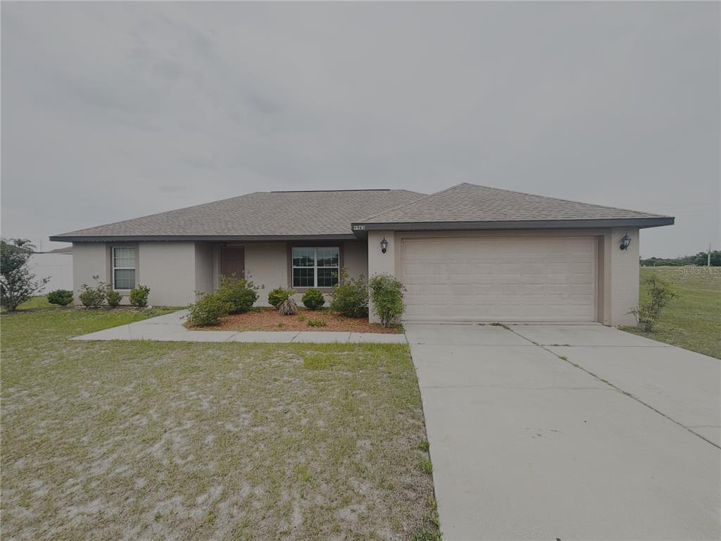 A single-story house with a beige exterior, a two-car garage, and a front lawn — 9965 SW 55TH AVENUE ROAD, OCALA, FL