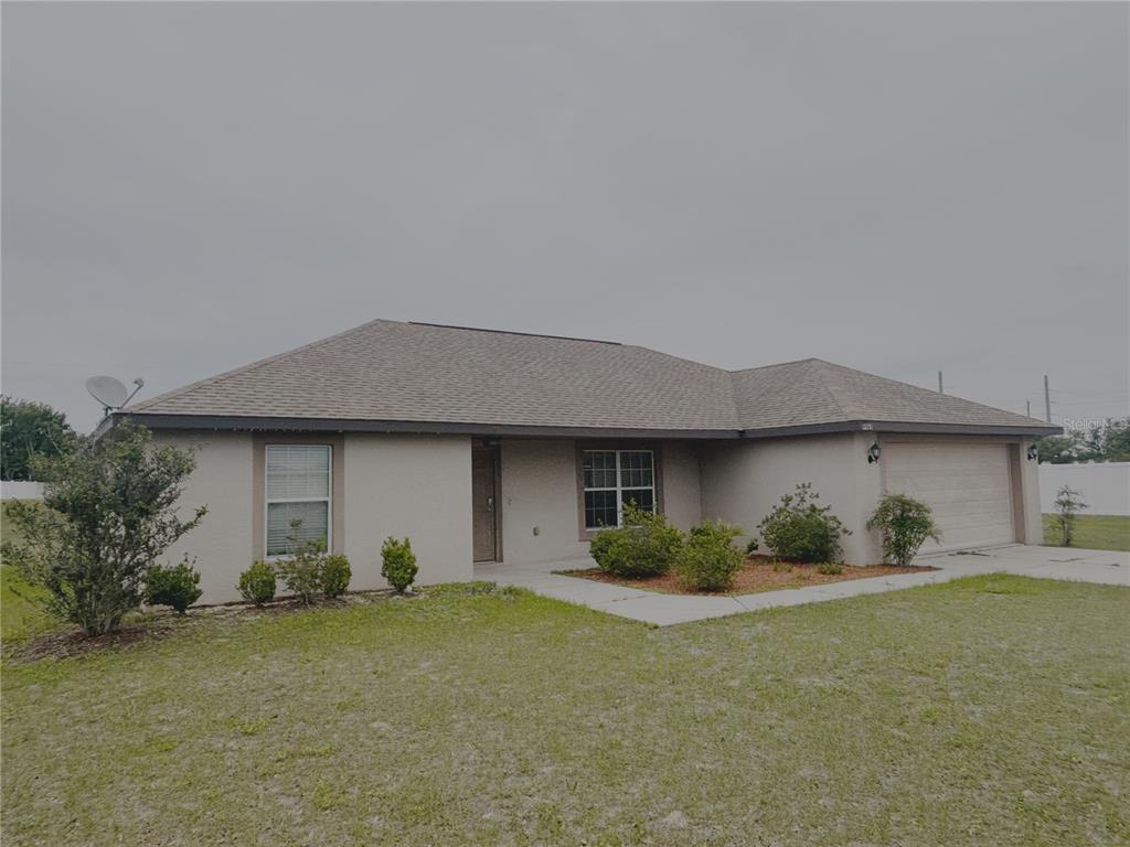 A single-story house with a beige stucco exterior, a shingled roof, and an attached garage — 9965 SW 55TH AVENUE ROAD, OCALA, FL