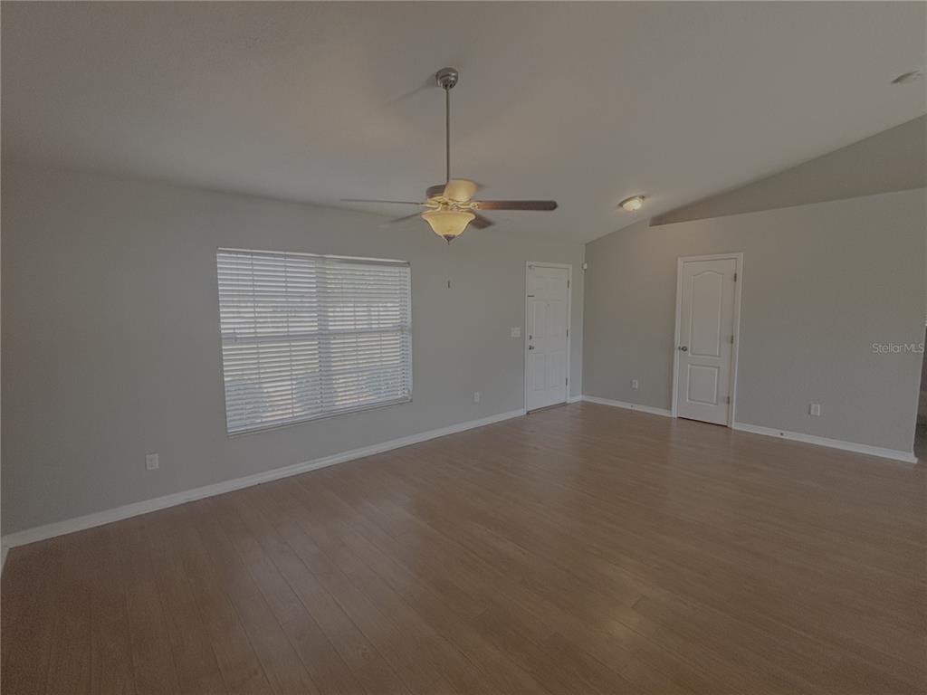 A living room features light wood flooring, gray walls, a ceiling fan, and a white door — 9965 SW 55TH AVENUE ROAD, OCALA, FL
