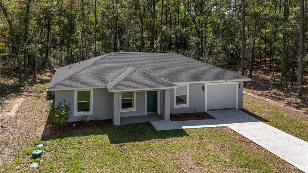 An elevated exterior view of a gray single-story house with a dark shingled roof — 15664 SW 28TH LANE, OCALA, FL