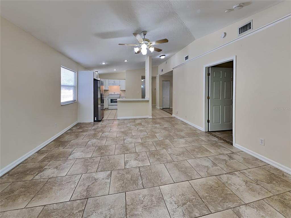 An open-concept living and dining area features beige tile flooring and a ceiling fan — 155 PLAIN VIEW DRIVE UNIT B, PALM COAST, FL