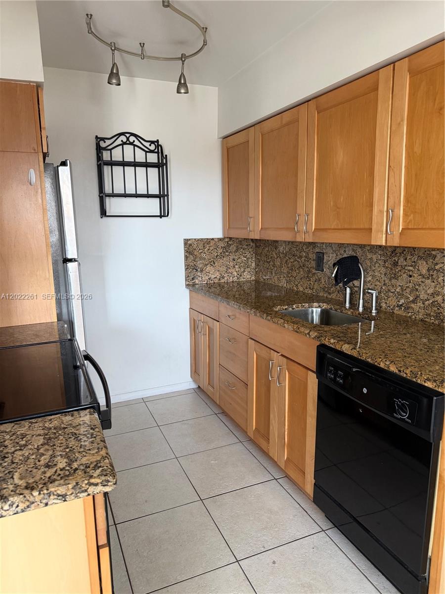 A kitchen features light wood cabinets, granite countertops, a black dishwasher, and tile flooring — 4043 Cornwall C # 4043, Boca Raton FL 33434, BOCA RATON, FL