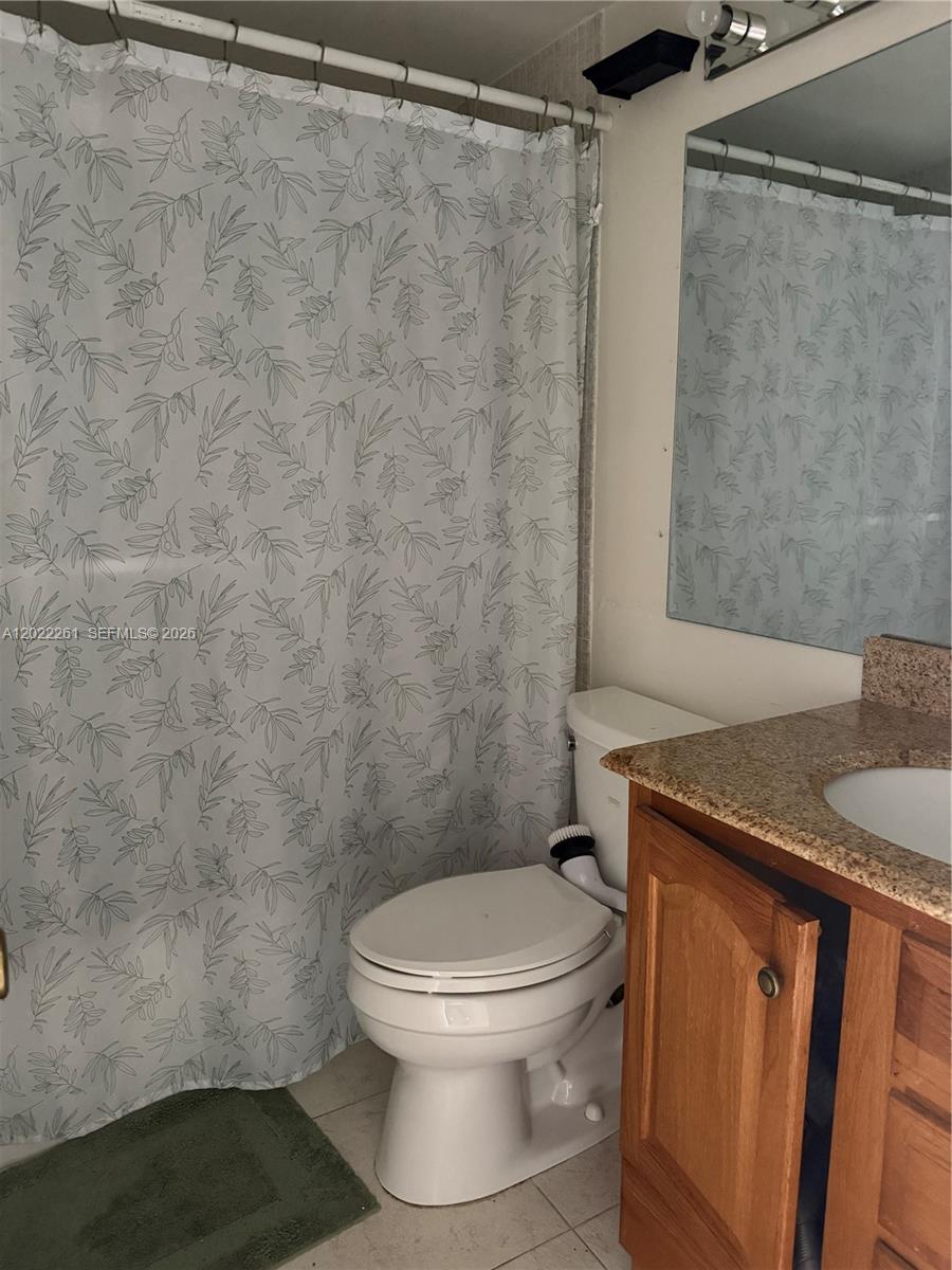 A bathroom features a wood vanity with a granite countertop, a toilet, and a shower curtain — 4043 Cornwall C # 4043, Boca Raton FL 33434, BOCA RATON, FL