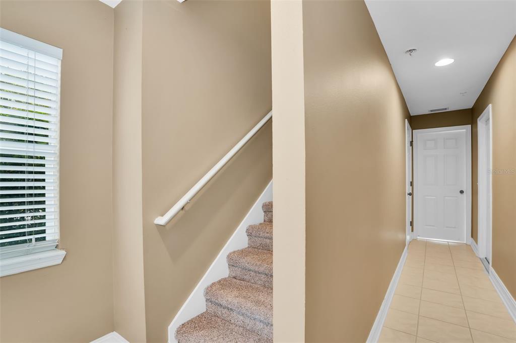 A carpeted staircase with a white handrail sits beside a hallway with tiled floors — 3102 TOSCANA CIRCLE, TAMPA, FL