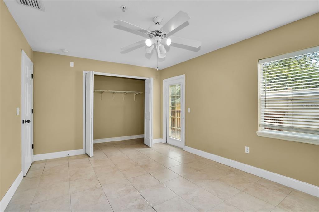 A bedroom with tan walls, tile flooring, a ceiling fan, a closet, and a door — 3102 TOSCANA CIRCLE, TAMPA, FL
