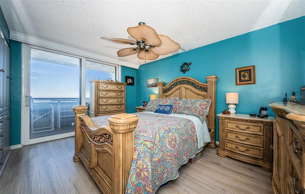A bedroom with a wooden bed frame, teal walls, and a sliding door to a balcony — 6035 SEA RANCH DRIVE UNIT 505, HUDSON, FL