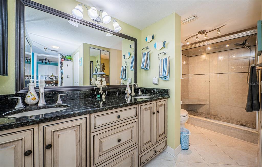 A bathroom features a double vanity with dark granite countertops and a glass-enclosed walk-in shower — 6035 SEA RANCH DRIVE UNIT 505, HUDSON, FL