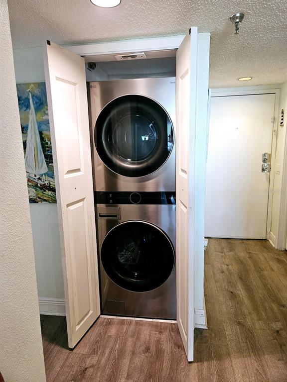 A stainless steel stacked washer and dryer unit sits inside a closet in a hallway — 6035 SEA RANCH DRIVE UNIT 505, HUDSON, FL