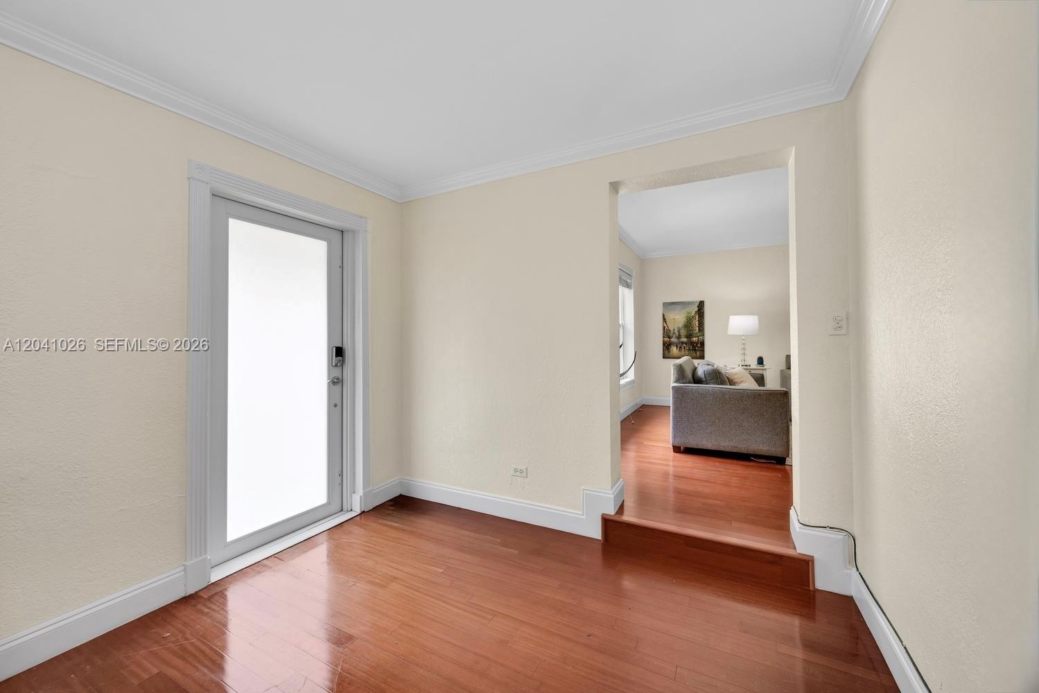 An entryway with hardwood floors leads to a sunken living room through a doorway — 829 Medina Ave, Coral Gables FL 33134, CORAL GABLES, FL