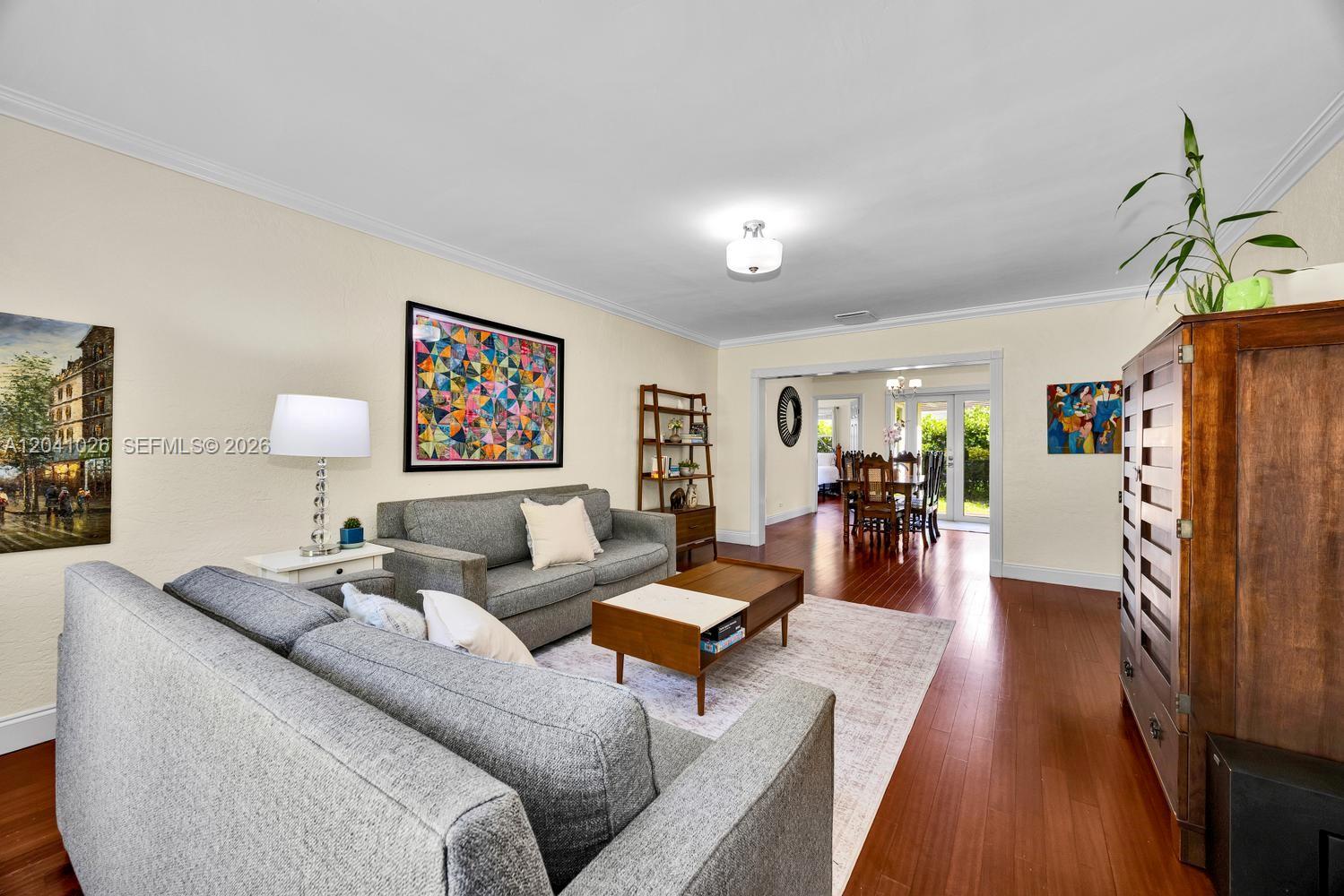 A living room features gray sofas, a wooden coffee table, and hardwood flooring — 829 Medina Ave, Coral Gables FL 33134, CORAL GABLES, FL