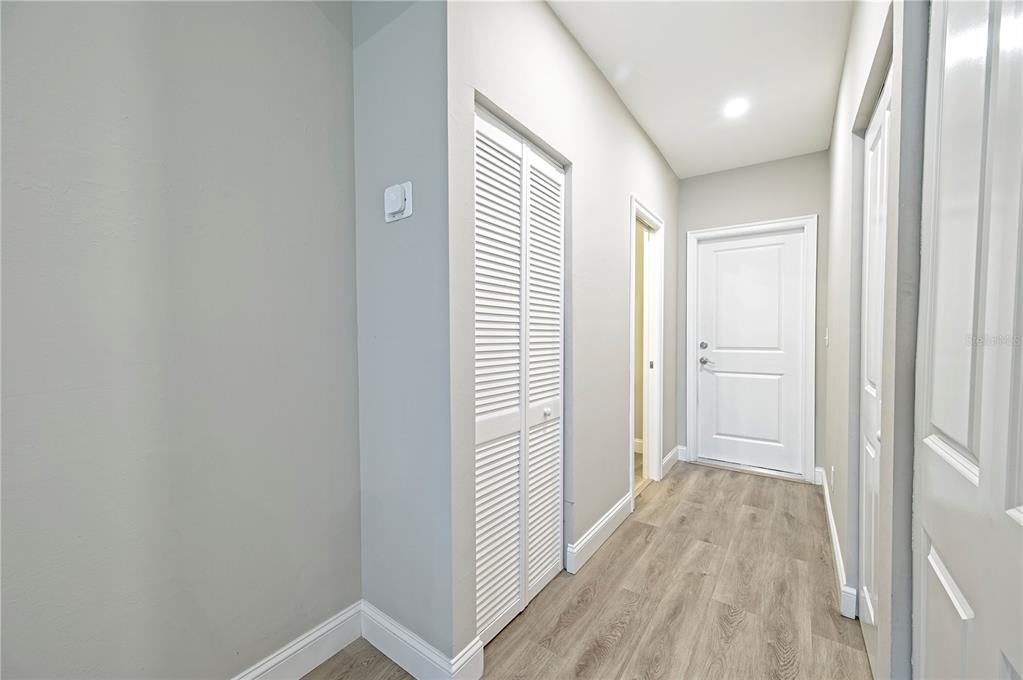 A hallway features light gray walls, wood-look flooring, a louvered closet door, and white trim — 1826 KIRKWOOD STREET, NORTH PORT, FL