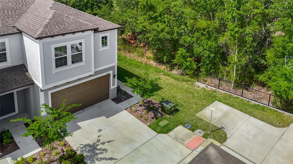An aerial view shows a two-story house with a garage, driveway, and adjacent wooded area — 10801 FORT WHITE COURT, TAMPA, FL