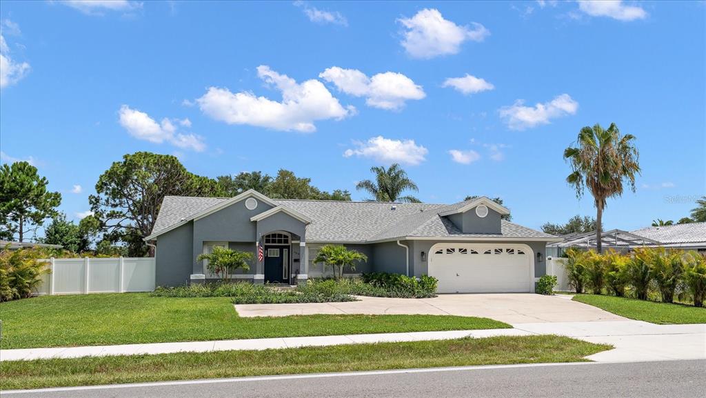 A gray single-story house with a white garage door and a white vinyl fence — 668 MEHLENBACHER ROAD, BELLEAIR, FL