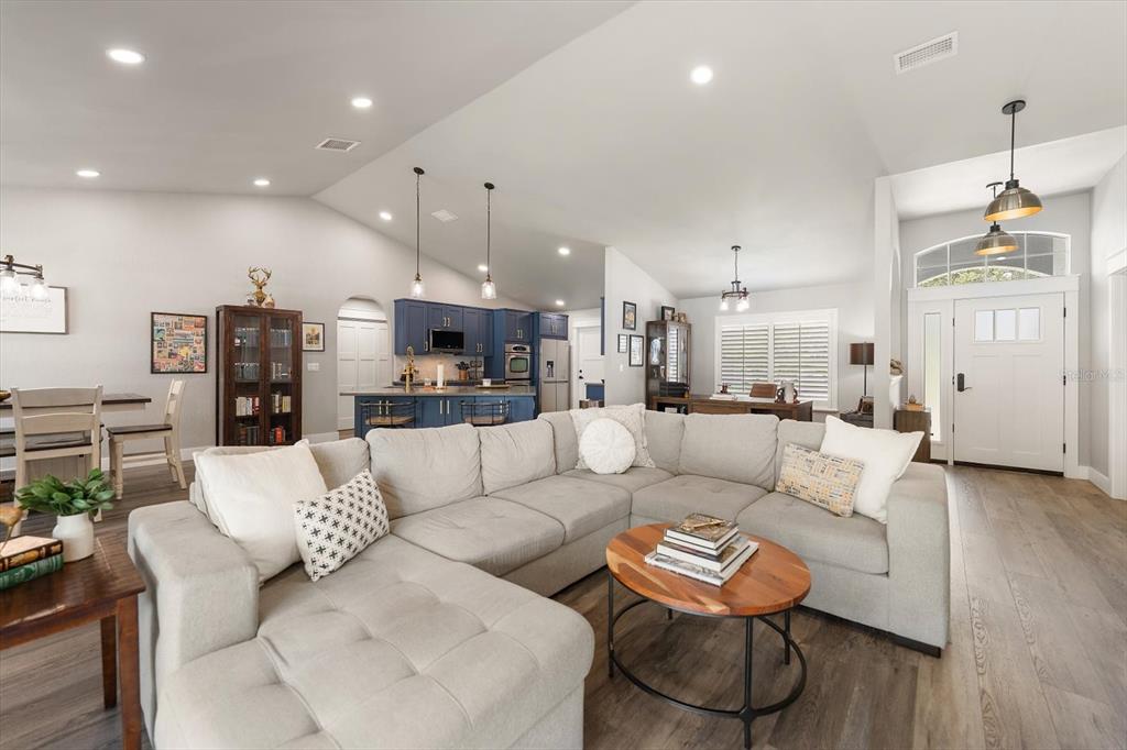 A spacious open-concept living room features a large sectional sofa, kitchen island, and entryway — 668 MEHLENBACHER ROAD, BELLEAIR, FL