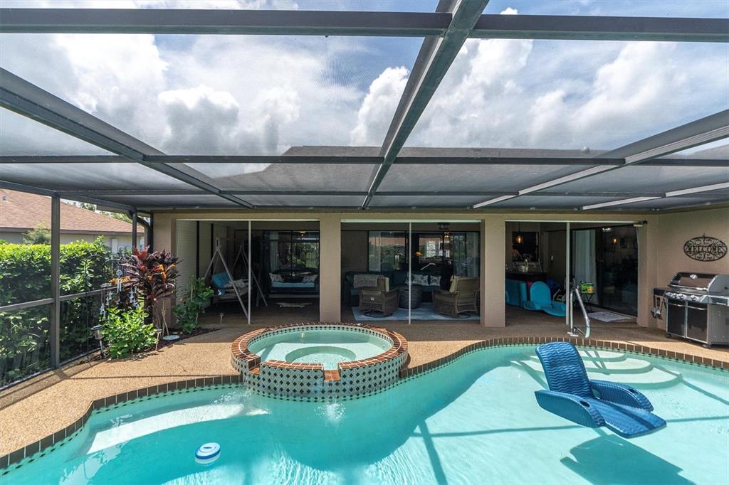 A screened-in patio features a swimming pool, a raised hot tub, and outdoor furniture — 301 THORN HILL PLACE, SUN CITY CENTER, FL