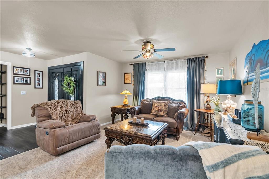 A living room features a brown recliner, a loveseat, a coffee table, and blue curtains — 301 THORN HILL PLACE, SUN CITY CENTER, FL
