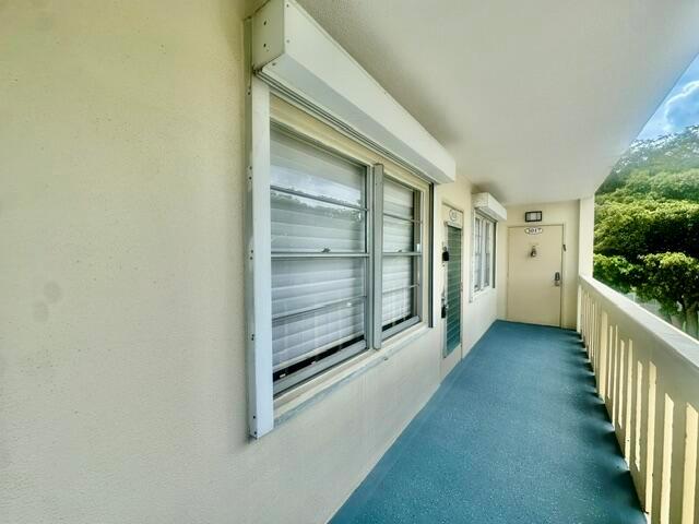 An exterior walkway features a window with a metal shutter, a door, and a railing — 3018 Ainslie B, Boca Raton FL 33434, BOCA RATON, FL