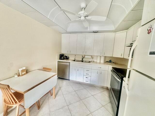 A kitchen features white cabinets, light-colored tile flooring, a dining table, and a ceiling fan — 3018 Ainslie B, Boca Raton FL 33434, BOCA RATON, FL
