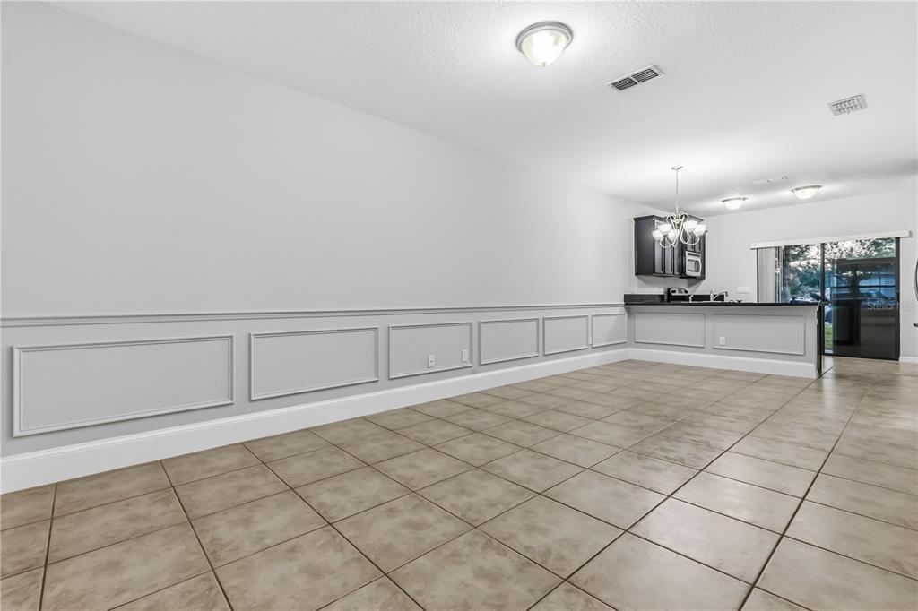 An open-concept dining area features light gray walls with wainscoting, tile flooring, and recessed lighting — 1251 TRILLIUM PARK LANE, SANFORD, FL