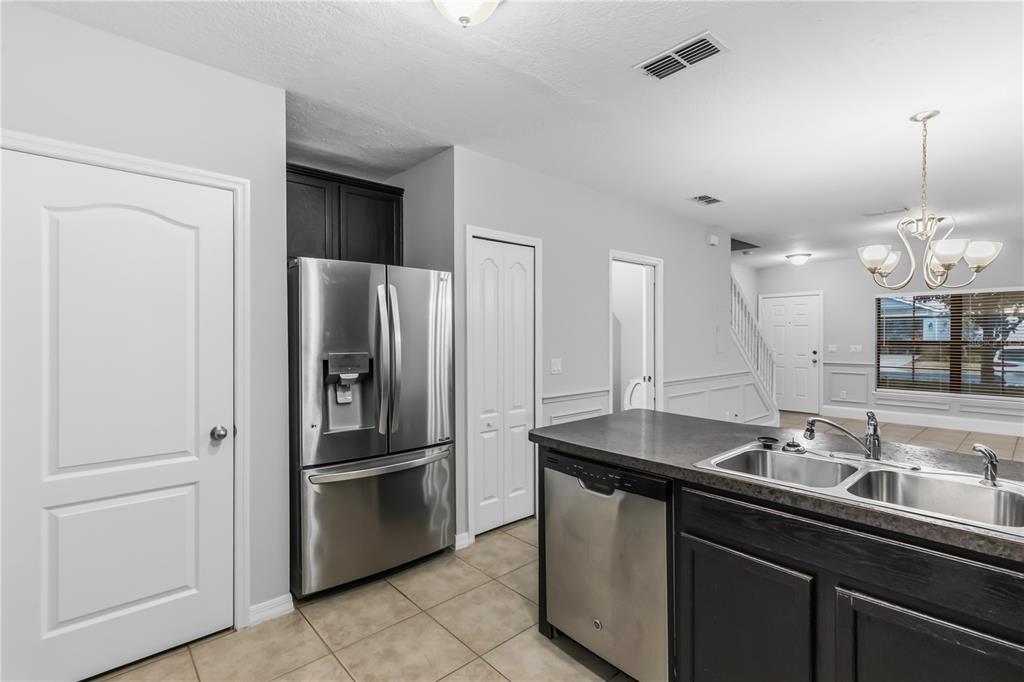 A kitchen with stainless steel appliances, dark cabinets, and an island with a double sink — 1251 TRILLIUM PARK LANE, SANFORD, FL