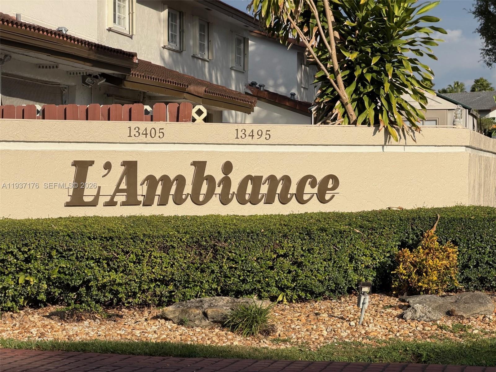 A beige stucco wall displays the name L'Ambiance above a manicured hedge and landscaping — 13551 SW 62nd St # 4 # 155, Miami FL 33183, MIAMI, FL