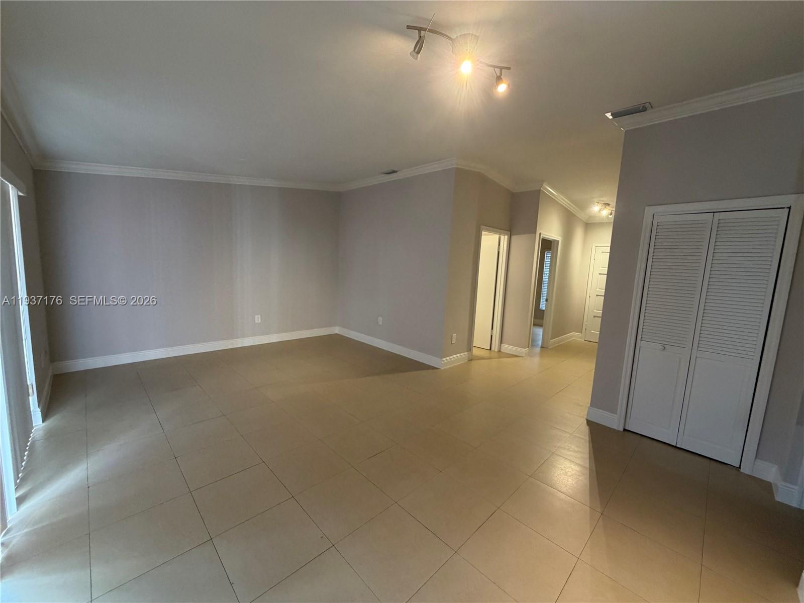 An empty room features light-colored tile flooring, neutral walls, and a white louvered closet door — 13551 SW 62nd St # 4 # 155, Miami FL 33183, MIAMI, FL